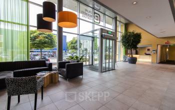 Moderne ontvangsthal in kantoorpand op Meander 251, Arnhem IJsseloord met zitgedeelte en leestafel.