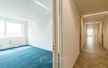 Leeg kantoorpand op Delta 1, Arnhem IJsseloord met tapijt en lange gang, ideaal voor wie kantoorruimte wil huren.