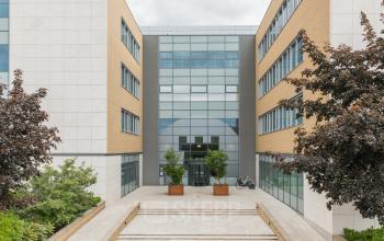 Het moderne kantoorpand op Delta 1, Arnhem IJsseloord, met een strakke glazen entree geflankeerd door bakstenen gevels en omgeven door groen. Geschikt voor kantoorruimte huren in een professionele omgeving.