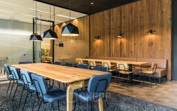 Moderne kantineruimte in kantoorpand gelegen op Delta 1, Arnhem IJsseloord, met houten wanden, lange tafels en blauwe stoelen. Ideaal voor kantoorruimte huren door bedrijven die comfort en stijl waarderen.