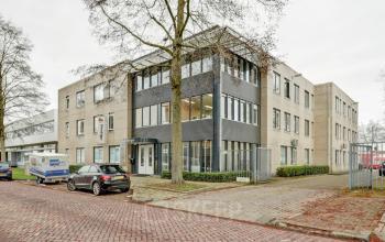 Kantoorpand aan de Bruningweg 23 in Arnhem IJsseloord met moderne uitstraling. Geschikt voor bedrijven die kantoorruimte willen huren. Voor de deur staan auto's geparkeerd.