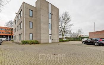 Exterieur van kantoorpand Bruningweg 23 in Arnhem IJsseloord met parkeerplaats. Kantoorruimte huren in moderne omgeving, met auto’s op de parkeerplaats. Veilige toegang en groene omgeving.