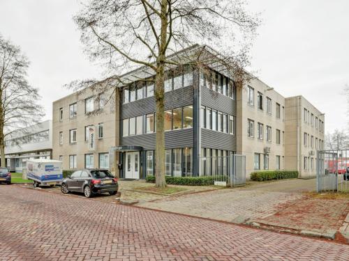 Kantoorpand aan de Bruningweg 23 in Arnhem IJsseloord met moderne uitstraling. Geschikt voor bedrijven die kantoorruimte willen huren. Voor de deur staan auto's geparkeerd.