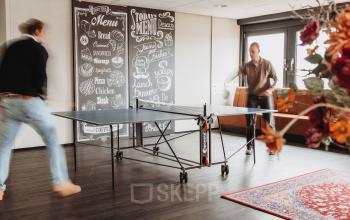 Moderne kantoorruimte met tafeltennistafel in Arnhem IJsseloord. Twee mensen spelen tafeltennis, ideaal voor ontspanning tijdens werktijd. Unieke kans om kantoorruimte te huren in dit kantoorpand op Vlamoven 34.