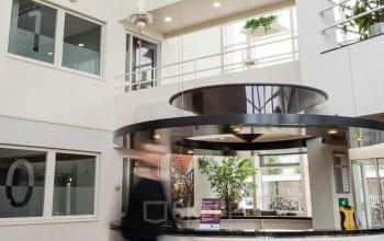 Lichte en ruime entree van een kantoorpand op Vlamoven 34 in Arnhem IJsseloord, met een receptiebalie en moderne uitstraling. Ideaal om kantoorruimte te huren in een dynamische omgeving.