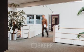 Kantoorruimte op Vlamoven 34 in Arnhem IJsseloord met moderne inrichting en rustige kleuren. Personen voeren zakelijke activiteiten uit in de kantoorpand. Ideaal voor kantoorruimte huren.