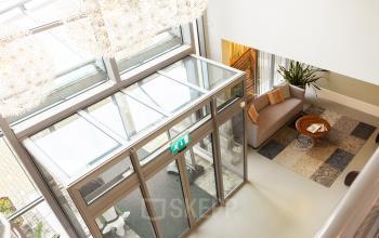 Ingang van een kantoorpand op Mr D.U. Stikkerstraat 10, Arnhem Zuid, met moderne glazen deuren en een ontvangstruimte met zithoek.