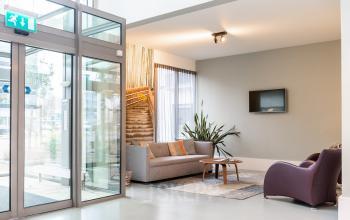 Moderne ontvangstruimte van het kantoorpand op Mr D.U. Stikkerstraat 10 in Arnhem Zuid, Arnhem, met banken, stoelen en een glazen entree.