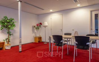 Kantoorruimte huren in Arnhem Zuid aan de Kronenburgsingel 525 met een rode vloerbedekking en enkele stoelen rondom een tafel.