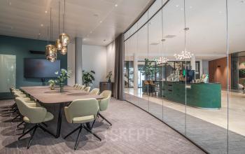 Moderne kantoorruimte te huur op Rijksweg-West 2 in Arnhem Zuid met een vergadertafel, stoelen en een glazen wand die een lounge scheidt.