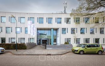 Vooraanzicht van kantoorpand op Amalialaan 126 in Baarn; modern gebouw met strakke gevel en parkeerplaats. Ideaal voor kantoorruimte huren.