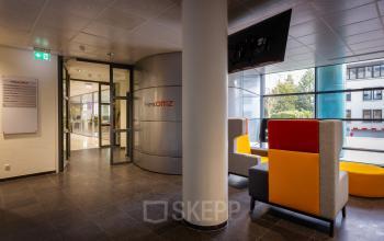 Kantoorruimte te huur in Baarn aan Amalialaan 126, met moderne ontvangsthal, kleurrijke zitplaatsen en glazen wanden voor een open uitstraling.
