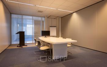 Vergaderruimte in kantoorpand op Amalialaan 126, Baarn met moderne tafel, stoelen en presentatiescherm, ideaal voor kantoorruimte huren.