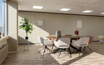 Moderne kantoorruimte met een ronde vergadertafel en comfortabele stoelen, gelegen aan de Kamerlingh Onnesweg 10 in Barendrecht. Ideaal voor wie een lichte en functionele kantoorpand wil huren.
