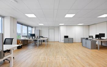 Ruime, lichte kantoorruimte met houten vloer en diverse bureaus op Kamerlingh Onnesweg 10, Barendrecht. Ideaal voor bedrijven die een open werkplek willen huren. Geschikt voor meerdere medewerkers.