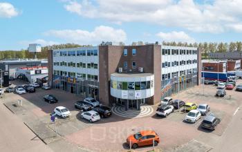 Exterieur van een kantoorpand aan de Kamerlingh Onnesweg 10 in Barendrecht, met meerdere geparkeerde auto's eromheen. Perfect voor wie kantoorruimte wil huren.