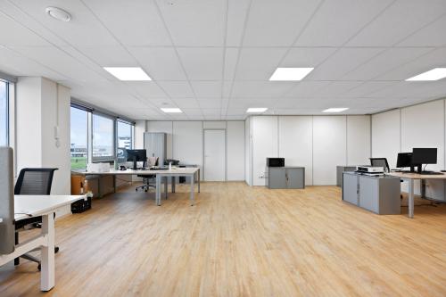 Ruime, lichte kantoorruimte met houten vloer en diverse bureaus op Kamerlingh Onnesweg 10, Barendrecht. Ideaal voor bedrijven die een open werkplek willen huren. Geschikt voor meerdere medewerkers.