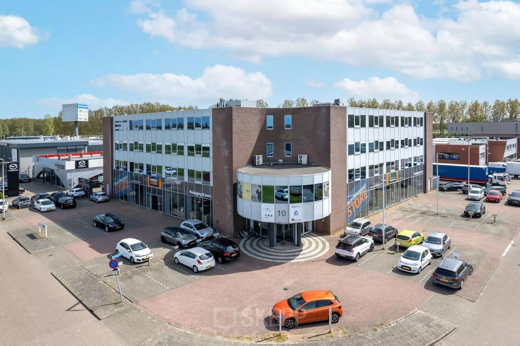 Exterieur van een kantoorpand aan de Kamerlingh Onnesweg 10 in Barendrecht, met meerdere geparkeerde auto's eromheen. Perfect voor wie kantoorruimte wil huren.