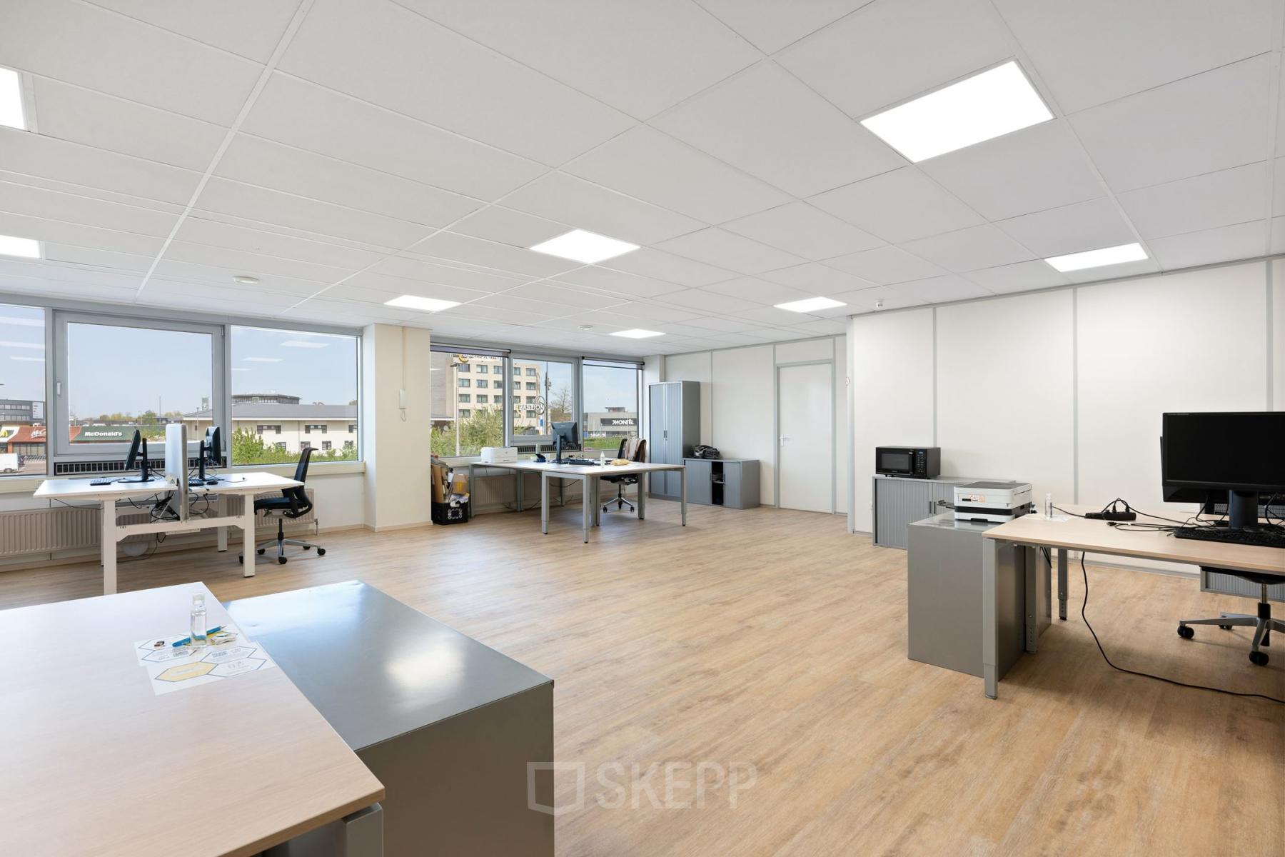 Kantoorruimte huren bij Kamerlingh Onnesweg 10 in Barendrecht, met werkplekken en grote ramen waardoor veel licht binnenvalt. Het kantoorpand biedt zicht op omliggende gebouwen met moderne werkstations.