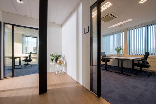 Interieur van kantoorruimte te huur op Veemweg 29-31 in Barneveld met werkplekken, houten vloer en ramen met jaloezieën.