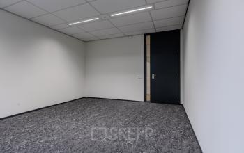 Lege kantoorruimte te huur aan de Rijtuigweg 10 in Bergen op Zoom, met grijze vloerbedekking en witte muren, klaar voor nieuwe inrichting.