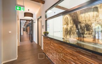 Ingang van een kantoorpand in Bergen op Zoom bij Blokstallen 2B, met een houten balie en doorkijk naar de gangen. Belicht door moderne lampen en versierd met planten.