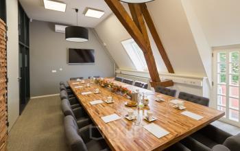 Vergaderruimte in een kantoorpand op Blokstallen 2B, Bergen op Zoom. Ruime tafel met luxe stoelen en groot raam, ideaal voor kantoorruimte huren. Modern ingericht met warme accenten.