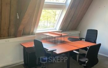 Kantoorruimte huren op Blokstallen 2B in Bergen op Zoom met houten balken, twee bureaus en stoelen bij een groot raam.