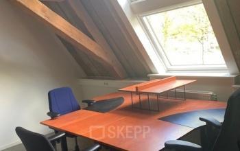 Kantoorruimte op Blokstallen 2B, Bergen op Zoom met een houten dak en grote ramen. Meubels met meerdere bureaus en stoelen zijn zichtbaar, ideaal voor kantoorruimte huren.