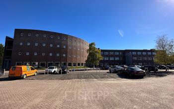 Exterieur van het kantoorpand aan De Maas 8, Best, met parkeerplaatsen voor het gebouw. Geschikt voor bedrijven die kantoorruimte willen huren.
