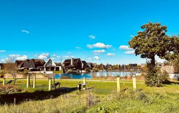 Buitengezicht van het kantoorpand op Deltazijde 20b, Blaricum. Veld en waterpartij op de voorgrond met moderne architectuur op de achtergrond. Ideaal voor wie een kantoorruimte wil huren in een rustige omgeving.