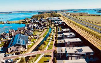 Luchtfoto van Blaricum aan de Deltazijde 20b, met uitzicht op een kantoorcomplex langs een snelweg en omliggende natuur. Ideaal voor kantoorruimte huren met aantrekkelijke omgeving.