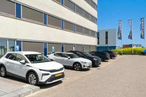 Parkeerplaats bij kantoorpand Tolnasingel 1-3 in Bodegraven met meerdere geparkeerde auto's naast een modern gebouw.
