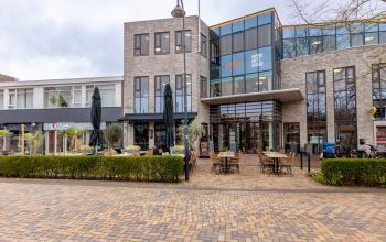 Modern kantoorpand op Marktstraat 1-7 in Bodegraven met glazen entree en terrastafels buiten. Ideaal voor kantoorruimte huren.