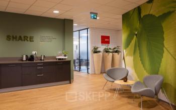 Moderne kantoorruimte op Marktstraat 1-7 in Bodegraven met groene wanden, ingerichte zithoek en koffiehoek. Ideaal voor bedrijven die kantoorruimte willen huren.