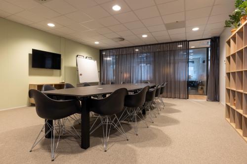 Moderne conferentieruimte met een lange zwarte tafel en stoelen, tegen een achtergrond van glazen wanden in een kantoorpand voor huur in Bodegraven.