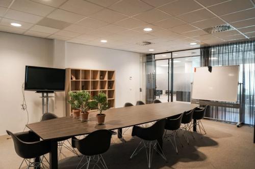 Vergaderruimte in kantoorpand aan de Marktstraat 1-7, Bodegraven, met lange tafel, stoelen, televisiescherm en whiteboard. Ideaal om kantoorruimte te huren voor zakelijke bijeenkomsten.