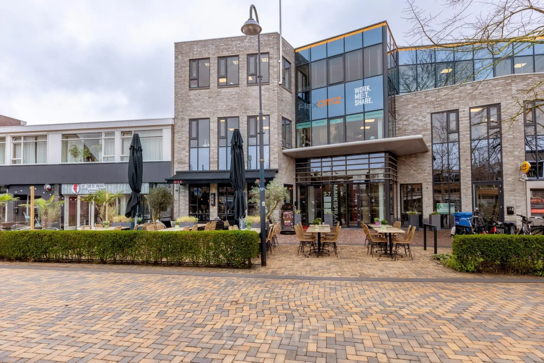Modern kantoorpand op Marktstraat 1-7 in Bodegraven met glazen entree en terrastafels buiten. Ideaal voor kantoorruimte huren.