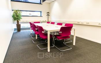 Vergaderruimte met roze stoelen rond een tafel in een kantoor op Ceresstraat 1, Breda Centrum-Station, geschikt voor kantoorruimte huren.