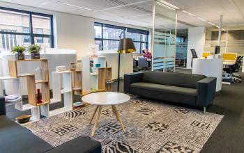 Moderne kantoorruimte huren aan Ceresstraat 1, Breda Centrum-Station, met comfortabele banken, decoratieve elementen en werkplekken met apparatuur.
