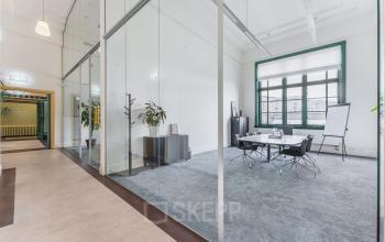Moderner kantoorpand met glazen wanden, vergadertafel, stoelen en flip-over op Ceresstraat 13 in Breda Centrum-Station. Ideaal om kantoorruimte te huren.