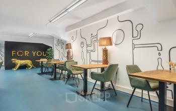 Moderne kantoorruimte te huur op Ceresstraat 13 in Breda Centrum-Station met kleurrijk interieur, beschilderde muren en diverse werkplekken ingericht met groene stoelen en houten tafels.