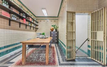Unieke kantoorruimte huren in een pand op Ceresstraat 13, Breda Centrum-Station, met karakteristieke tegelwanden en een houten bureau, ideaal voor creatieve zakelijke activiteiten.