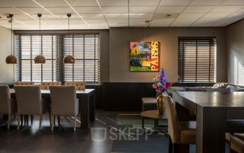 Moderne gemeubileerde kantoorruimte op Takkebijster 57A in Breda Oost-Brabantpark, voorzien van grote tafels en stijlvolle verlichting, ideaal om te huren voor zakelijke bijeenkomsten.