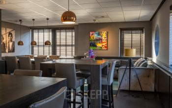 Gezellige kantoorruimte op Takkebijster 57A in Breda Oost-Brabantpark, voorzien van stijlvolle meubels en kleurrijke kunstwerken, perfect voor huur als creatieve werkplek.