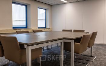 Kantoorruimte huren op Takkebijster 57A in Breda Oost-Brabantpark. Het kantoor toont een vergaderruimte met moderne stoelen en een grote tafel, ideaal voor zakelijke bijeenkomsten.