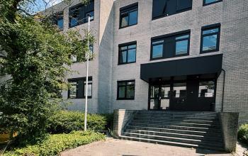 Het kantoorpand aan de Druivenstraat 25-31 in Breda Oost, geschikt voor kantoorruimte huren. De moderne gevel met grote ramen is omgeven door groen en betegelde paden.