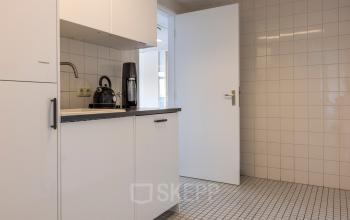 Kantoorruimte te huur aan de Druivenstraat 25-31 in Breda Oost, met een compacte kitchenette voorzien van een koffiezetapparaat en tegelwanden, ideaal voor kantoorgebruik.