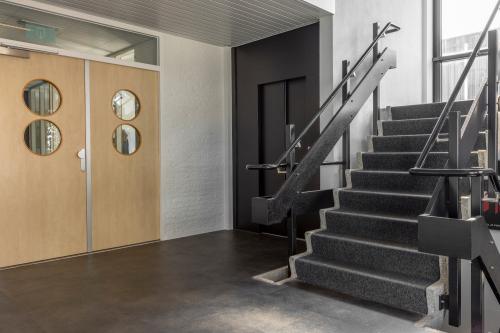Ingang van het kantoorpand op Druivenstraat 25-31 in Breda Oost, met een strakke trap en moderne deuren. Licht valt binnen via grote ramen.