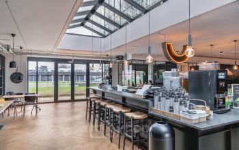 Modern ingerichte pantry in kantoorpand aan Rietbaan 2-12, Capelle aan den IJssel. Grote ramen en stijlvolle verlichting maken de ruimte licht en uitnodigend, ideaal voor een koffiepauze tijdens het huren van kantoorruimte.